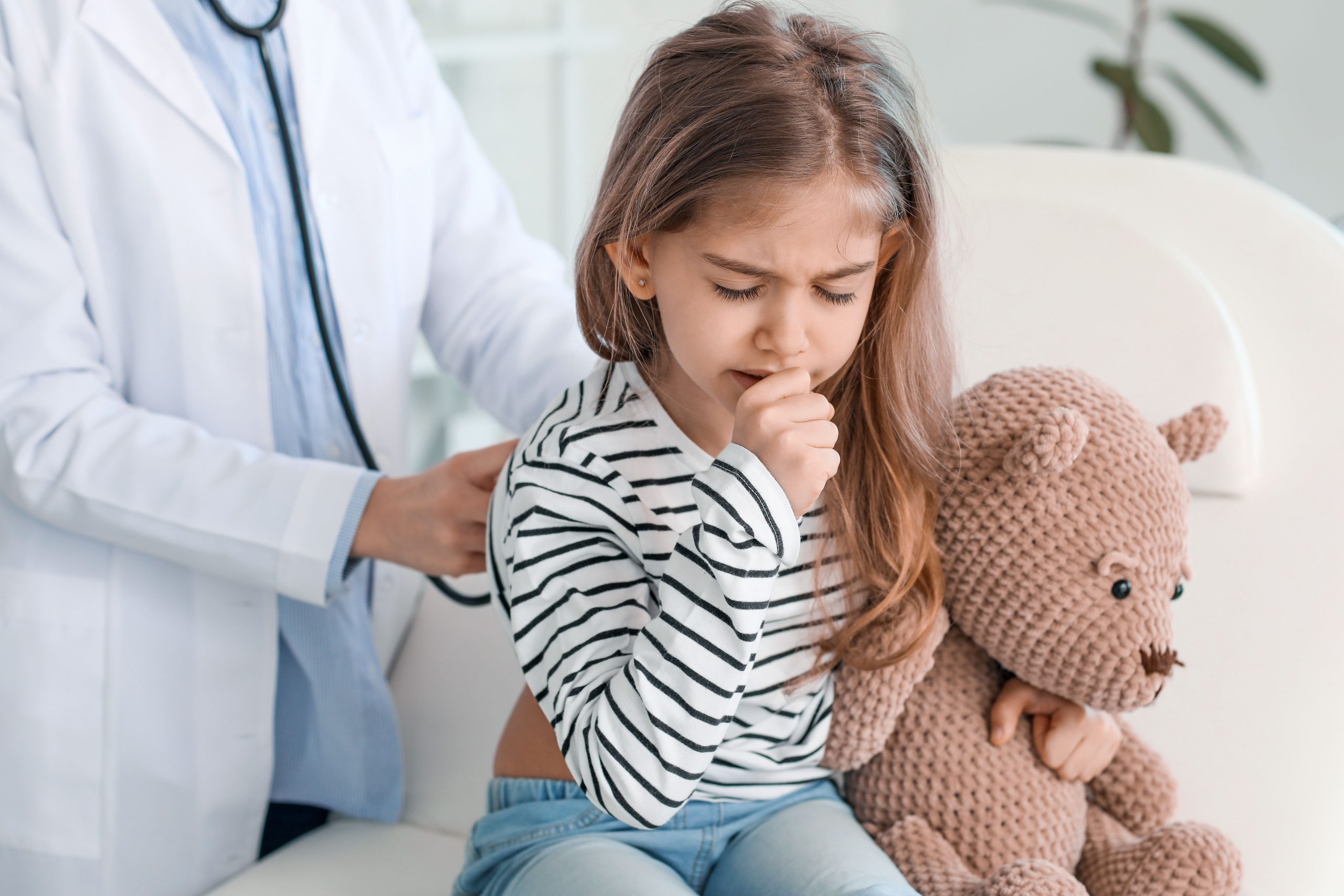 Child coughing whilst her lungs are being checked by doctor