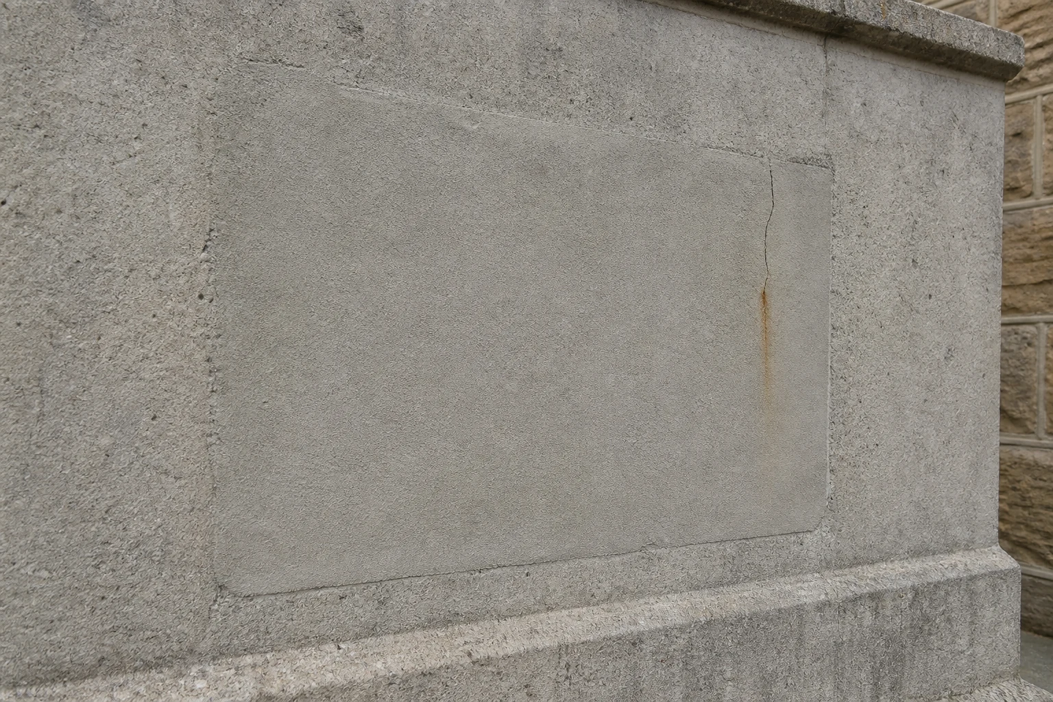 Concrete patch repair with a new rust-stained crack at the edge.